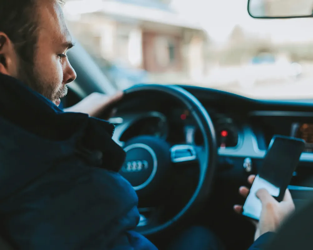Guy texting on phone while driving